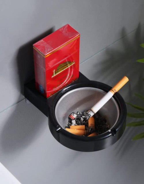 Dropdash wall mounted cigarette ashtray with a pack of cigarettes and ashes on a gray wall
