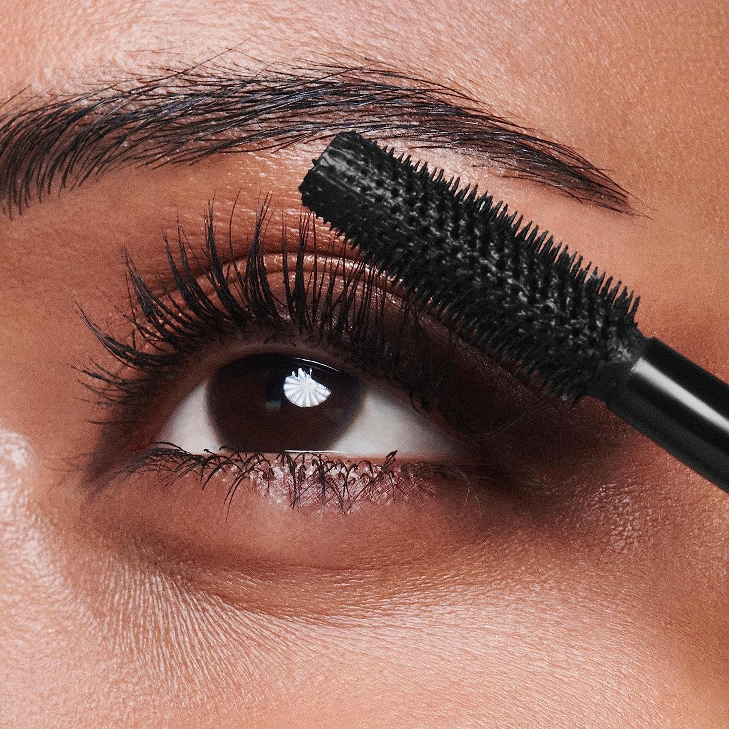 Close-up of eye applying long lasting mascara for dramatic lashes with volumizing brush