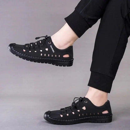 Black mens casual slip on shoes with cutout design and adjustable laces worn with black pants