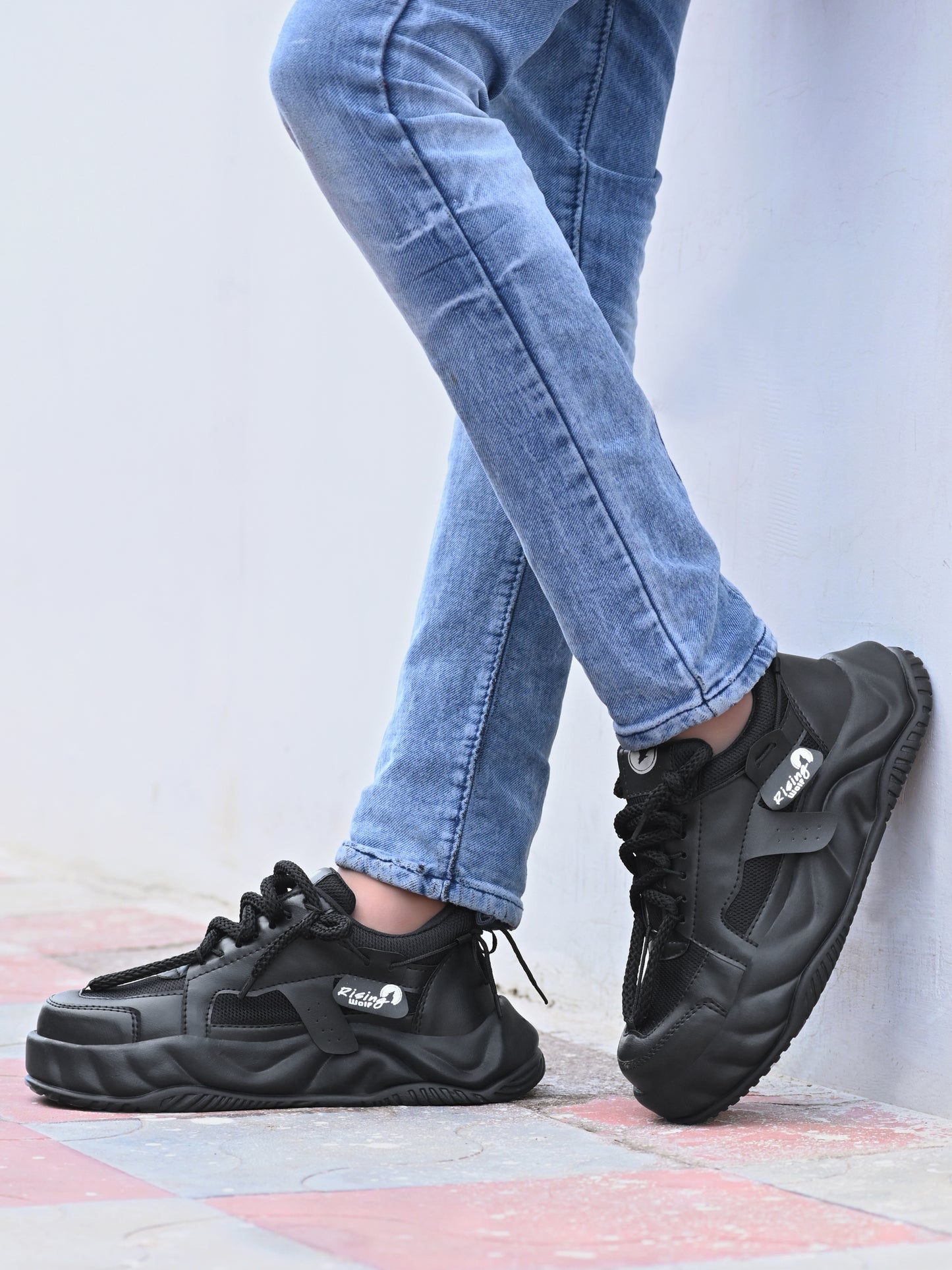 Mens comfortable black running shoes with cushioned sole worn with blue jeans outdoors