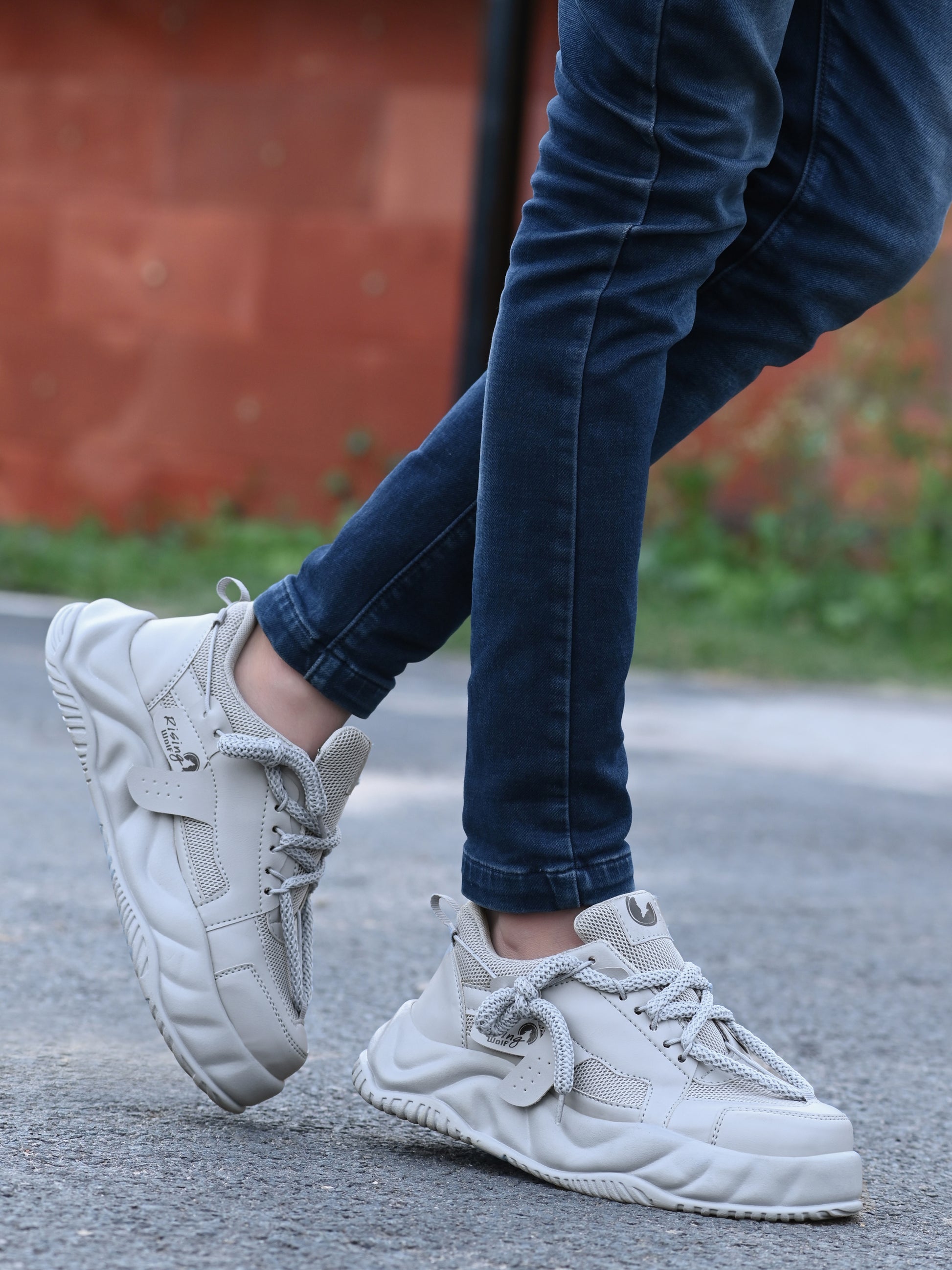 Mens comfortable grey running shoes worn with dark jeans outdoors on pavement