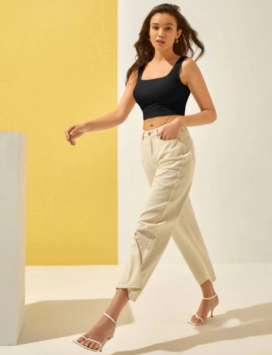 Model wearing a women's basic black tank top paired with high-waisted beige pants and white sandals